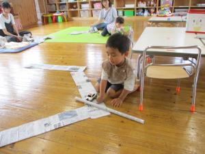 新聞紙で道路をつくり、おもちゃの車を走らせました。