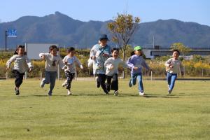 新地保育所　鹿狼山をバックに走る子ども達
